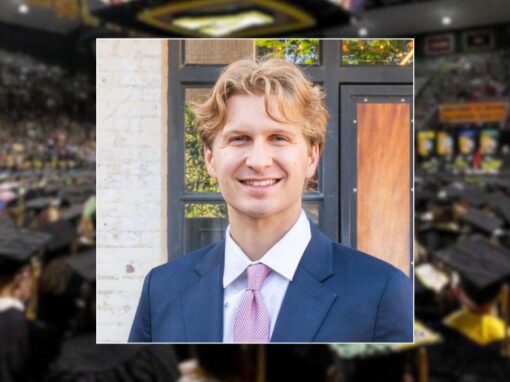 Zach Needles in suit, over a decorative background of App State graduation hats